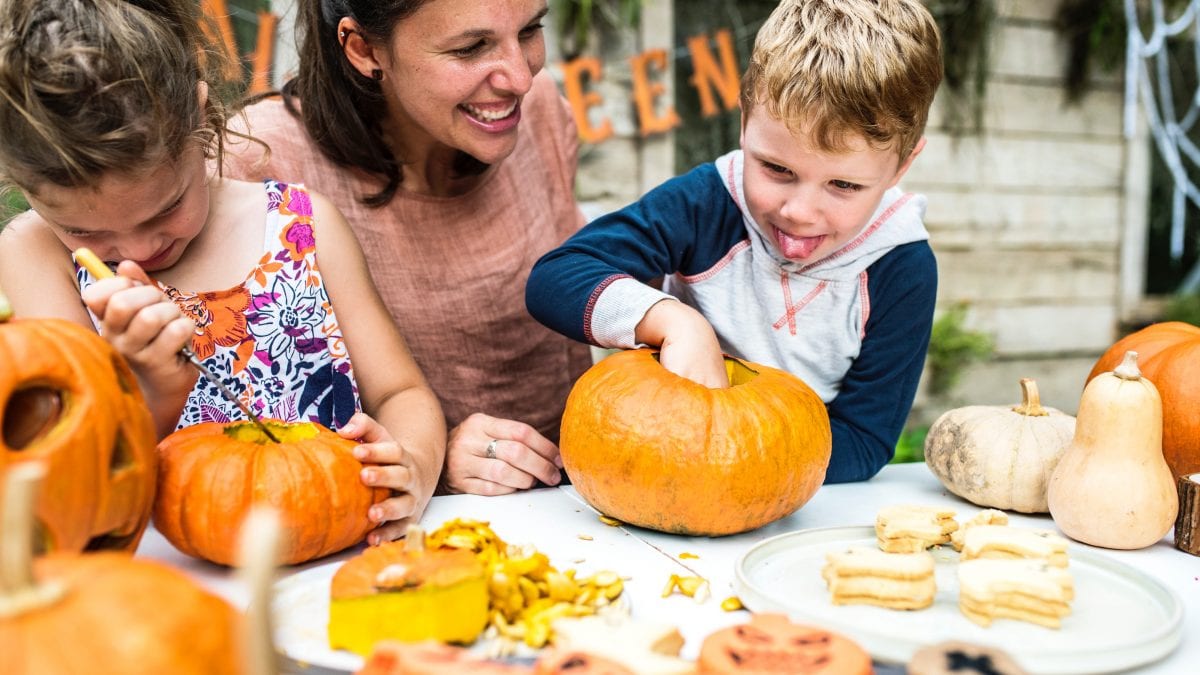 Mother with two children carving pumpkins