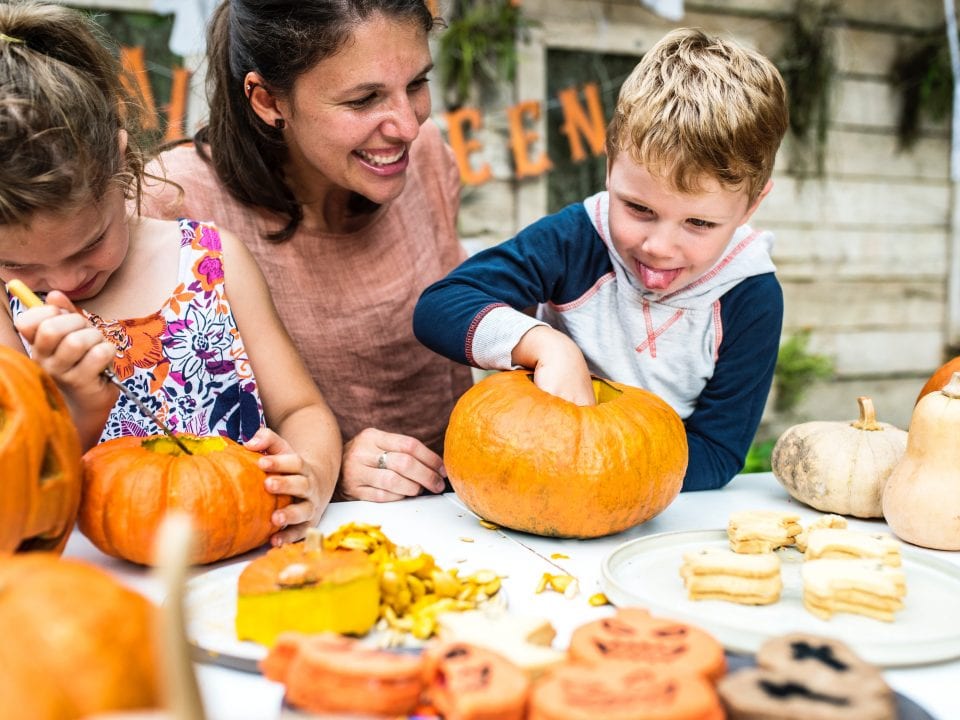 Mother with two children carving pumpkins