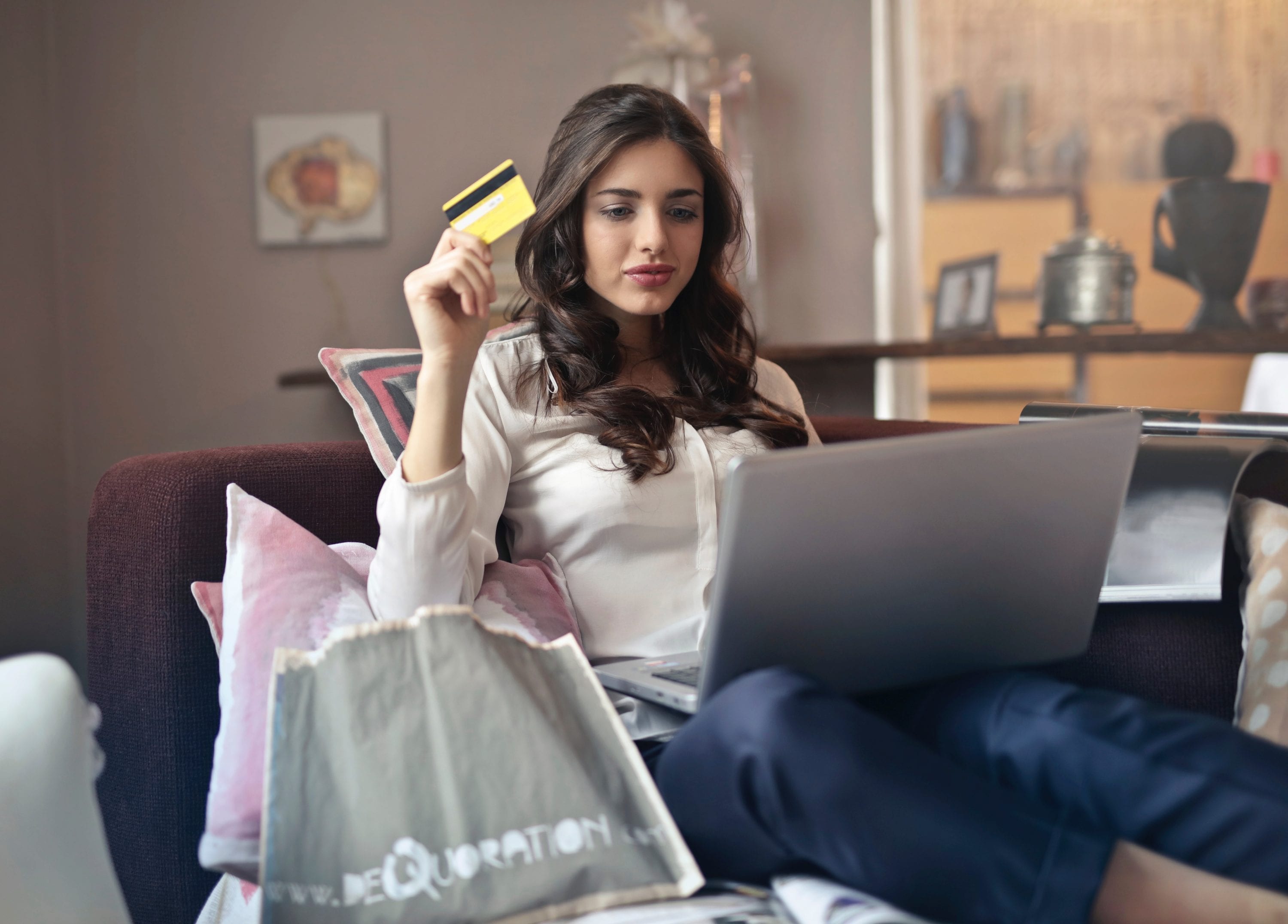 Lady sitting on couch using credit card online