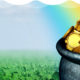 Pot of gold in field with four-leaf clovers and a rainbow in the sky