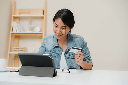 Woman looking at computer while holding credit card in hand