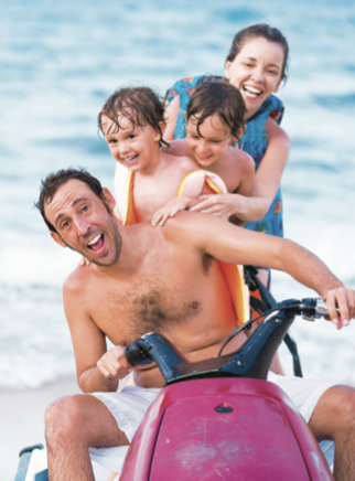 Father driving beach bike with mother and kids behind him