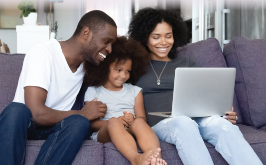 Family sitting on couch looking at computer