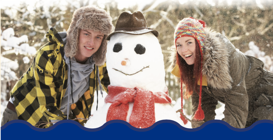 Young man and woman posing for picture with snowman