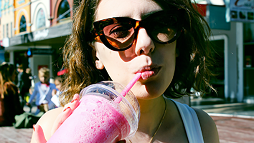 Young girl with sunglasses sipping on milkshake on boardwalk