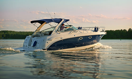 Man driving boat at sunset with still water and pretty sky.