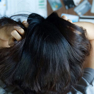 Frustrated woman with hands in hair looking down at credit cards and bills on table.