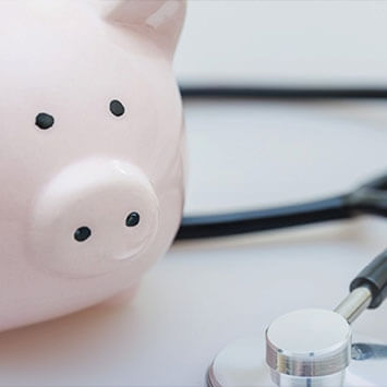 Piggy bank sitting on surface with stethoscope.