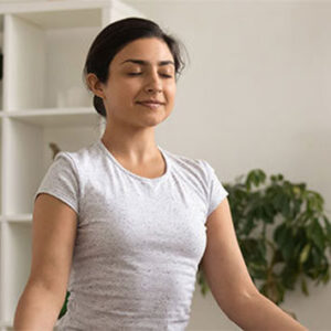 Woman sitting restfully while doing yoga with eyes closed.