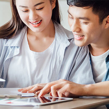 Couple sitting together at desk looking over documents.