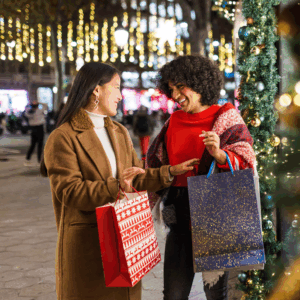 Two women holiday shopping and each holding a gift bag.