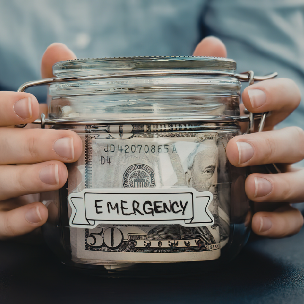 Personal holding a glass jar full of cash that says emergency on the front
