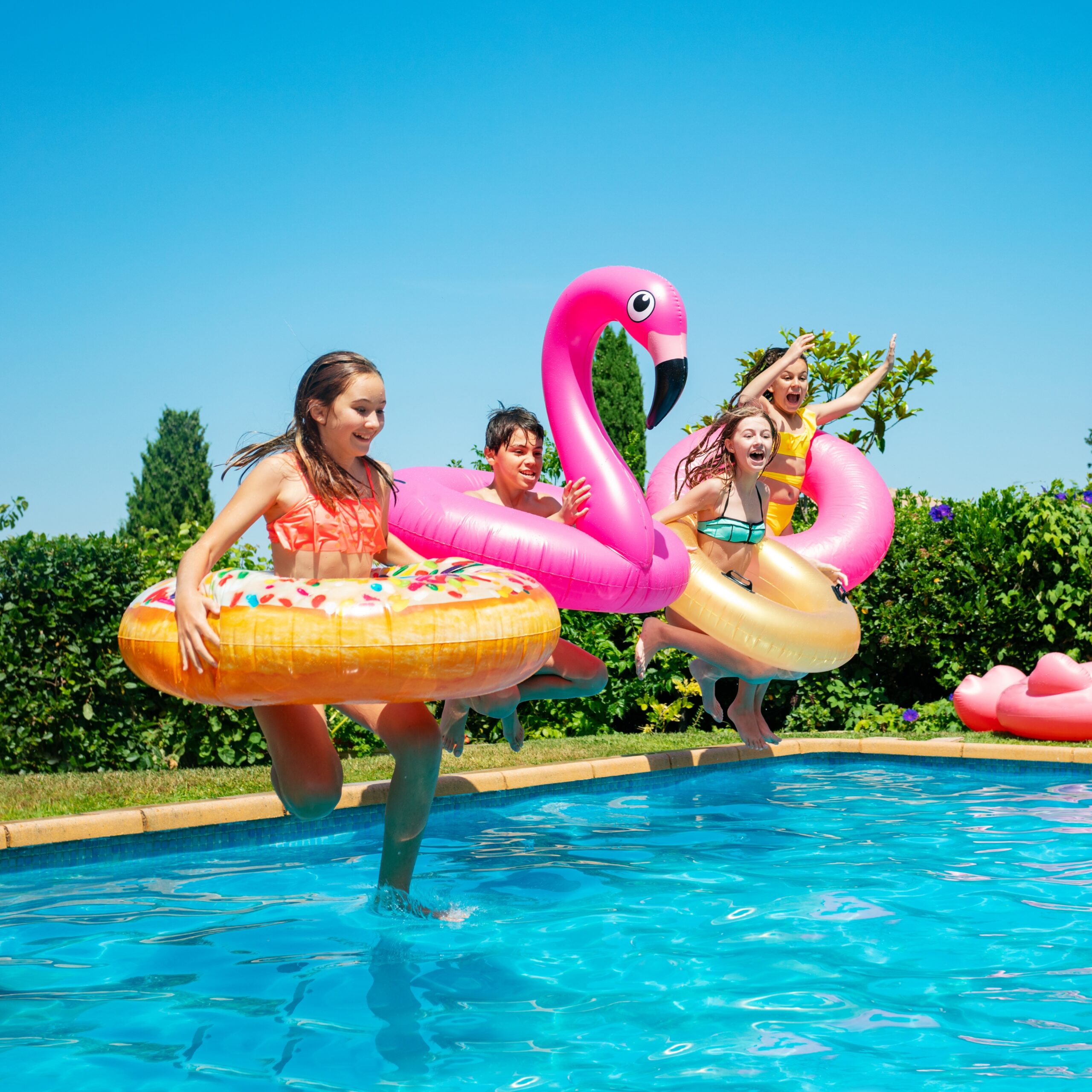 4 kids jumping into a pool with pool floats