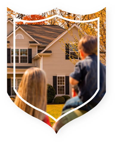 Family of three looking at house from front lawn with fall colored trees